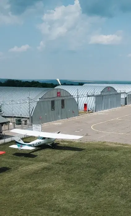 Hangare semirotunde lângă o pistă cu un avion mic