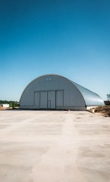 Hangar metalic semirotund pe o platformă betonată