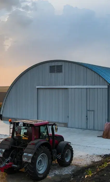 Tractor în fața unui hangar metalic semirotund