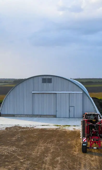 Hangar metalic semirotund cu poartă mare, în câmp