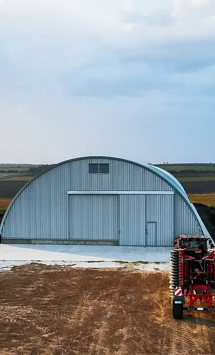 Hangar semirotund cu utilaj agricol roșu în față